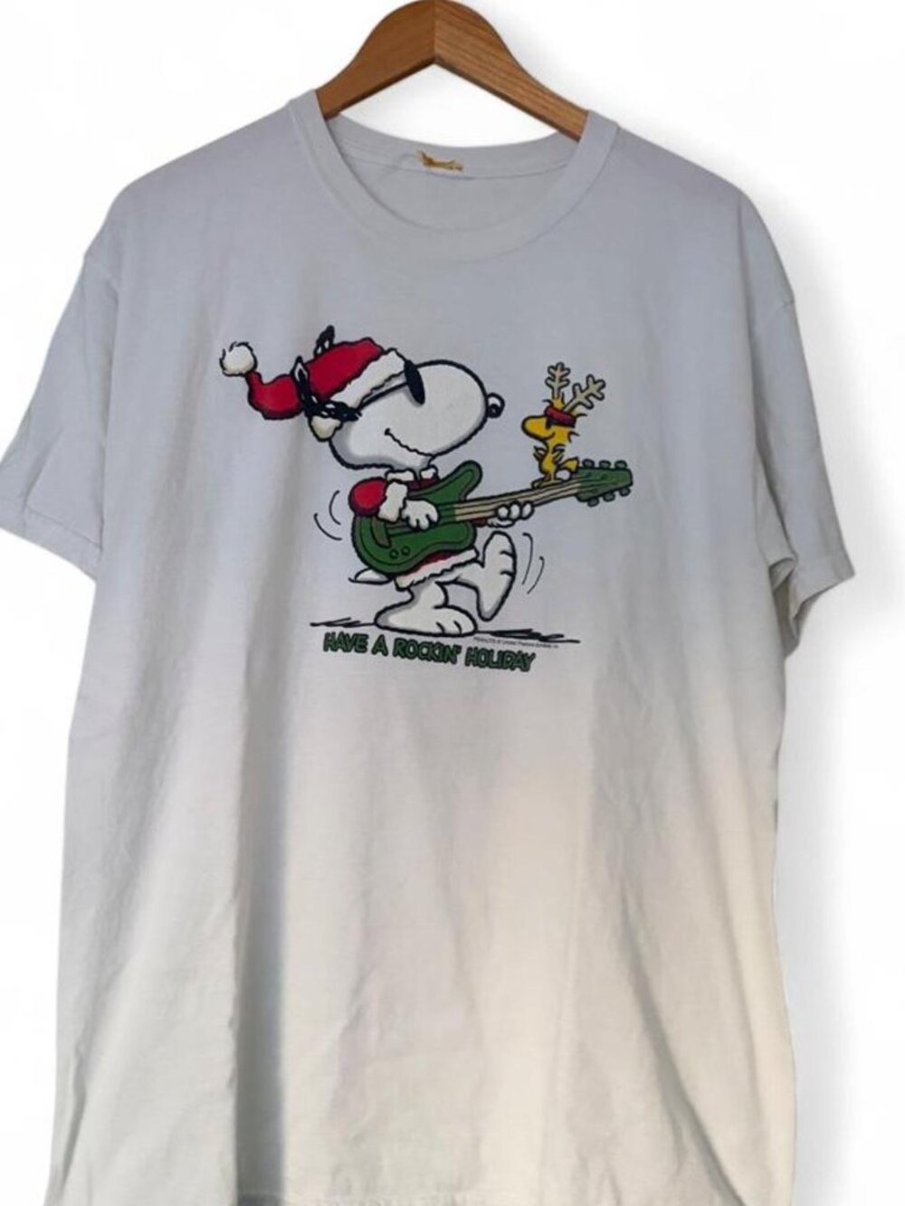 White Snoopy Christmas tee with graphic of Snoopy playing guitar with a reindeer
